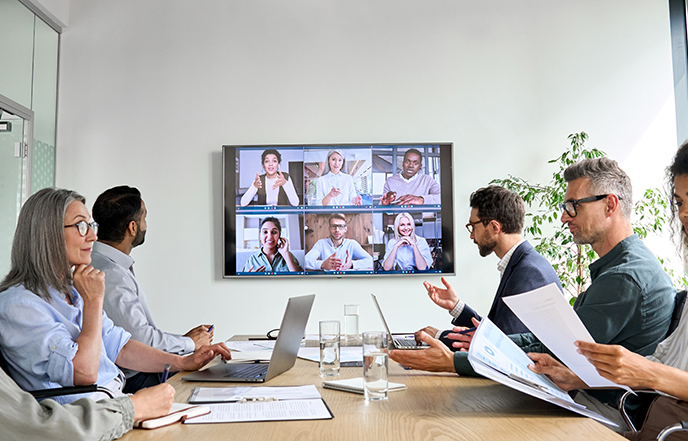 consultants on online conference video call on tv screen in conference room